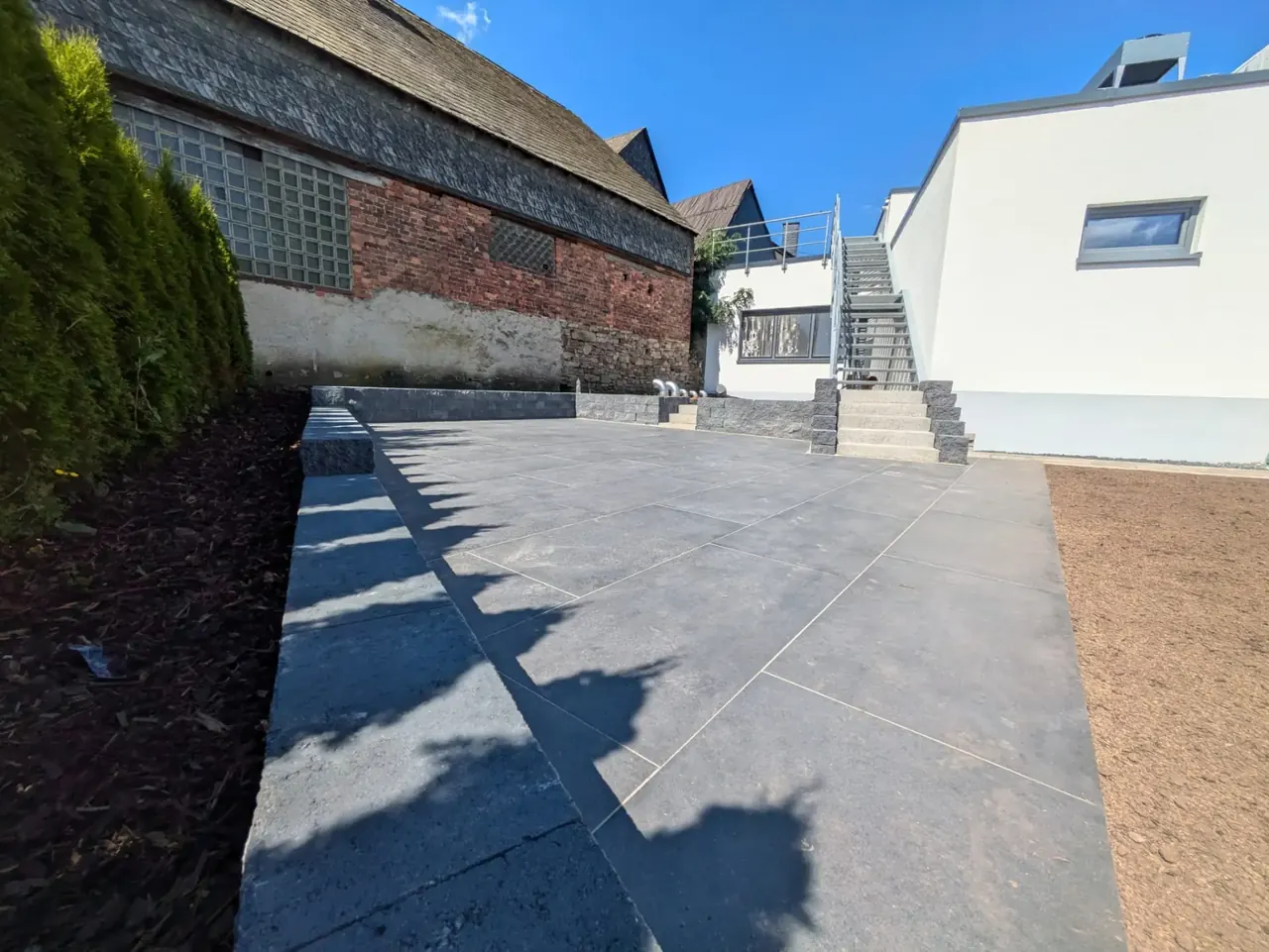 Großflächig verlegte Terrassenplatten mit Randeinfassung und Stufenanlage