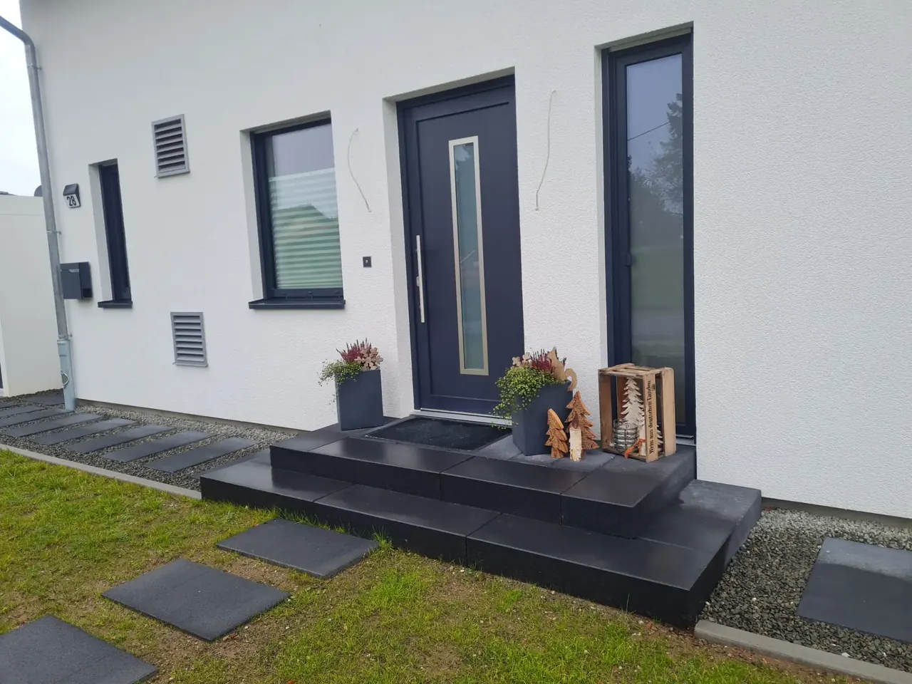 Hauseingang mit Blockstufen aus Naturstein und Trittplatten im Kiesbett