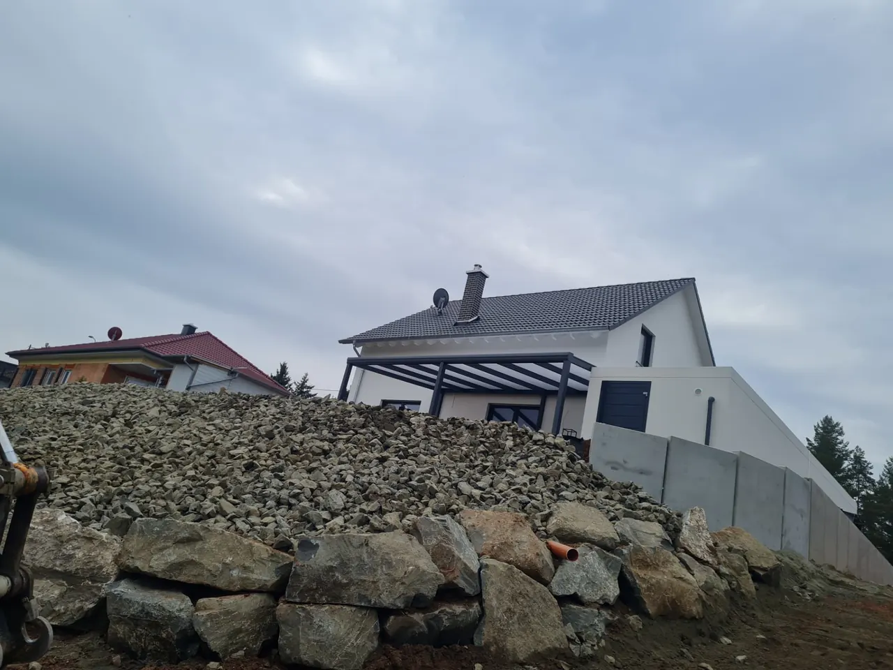 Massive Hangbefestigung aus Naturstein vor einem modernen Wohnhaus